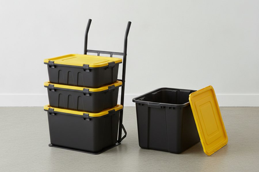Illustration of three black bins with yellow lids stacked on a hand truck dolly, with one open, empty bin beside them